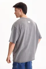 Remera oversize gris oscuro con efecto lavado, cuello redondo y mangas cortas amplias.