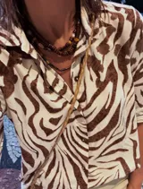 Camisa de fibrana de estilo clásico con estampa animal print zebra en tonos chocolate y blanco, con cuello camisero, mangas largas y botones de coco.