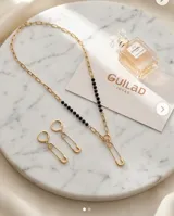 Set compuesto por collar y aros colgantes de acero con baño de oro, con diseño de dije en forma de alfiler de gancho.