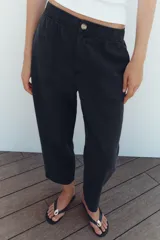 Pantalón de tiro medio color amarillo, con cintura elástica, bolsillos de plastrón en el delantero y pernera holgada que se estrecha hacia el tobillo. Cuenta con cierre frontal de cremallera y botón.