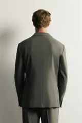 Blazer cruzada de traje color verde militar, de corte regular fit, con solapas de muesca, cierre frontal de doble botonadura, bolsillos con solapa en la cadera y bolsillo de vivo en el pecho.