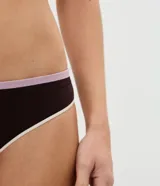 Bombacha bikini de diseño sin costura, confeccionada en poliamida marrón oscuro con detalles de bies contrastante en tono lila en la cintura y gris claro en las piernas.