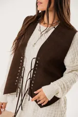 Chaleco marrón de gamuza con cordones laterales y tachas plateadas.