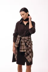 Vestido camisero de color marrón oscuro, con cuello clásico, cierre frontal de botones y mangas largas. Presenta un diseño de corte recto y largo midi.