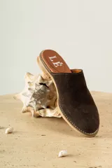 Mules de cuero negro con tachas plateadas en el borde de la suela y plantilla con logo estampado.