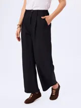 Pantalón barrel negro de corte ancho y relajado, confeccionado en poliéster con bolsillos laterales y cintura de tiro medio.