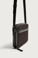 Bandolera combinada de diseño rectangular, confeccionada en gamuza marrón con detalles de cuero liso y correa larga ajustable. Cuenta con cierre principal de cremallera y bolsillo plano en el interior.