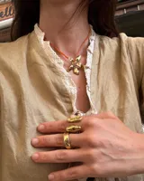 Collar tipo gargantilla con dije de flor metálica de acabado brillante, suspendido de un cordón doble de seda natural teñido a mano en color rojo.