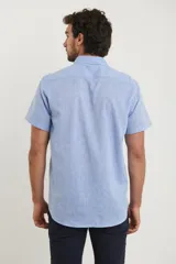 Camisa azul de manga corta, con cuello abotonado y bolsillo en el pecho.