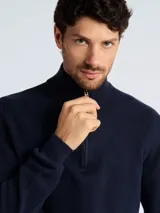 Sweater de punto color verde oscuro, con cuello alto y cierre frontal parcial, de manga larga y puños acanalados.