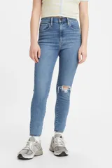 Jeans Levi's modelo Mile High Super Skinny de tiro súper alto, con ajuste ceñido en cadera, muslos y piernas hasta el tobillo. Presenta un diseño en denim azul con efecto desgastado y un detalle de rotura en la rodilla izquierda.