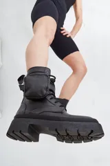 Borcego negro de cuero con base de goma track y detalle de bolsillo con cierre en el lateral.