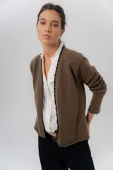 Saco básico de punto color marfil, confeccionado en lambswool, con corte entallado tipo chaquetita. Destaca por detalles de blonda tejida en los puños y a lo largo de la abertura frontal, con bordes en color contrastante.