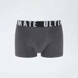 Pack de tres boxers de hombre. Uno es gris jaspeado liso, otro es negro con estampado de cruces blancas y el tercero es gris oscuro con estampado de camuflaje. Todos tienen cinturilla elástica blanca con texto negro.