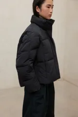 Campera acolchada negra, estilo puffer, con cuello alto y cierre frontal. Diseño oversize.