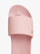 Ojotas tipo slide color rosa pálido, con pala ancha que presenta un patrón de monograma TH en relieve. Cuentan con una pequeña insignia metálica dorada del monograma TH en la tira y el logo de Tommy Hilfiger en relieve en la entresuela.