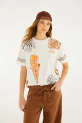Remera blanca de manga corta y cuello redondo de la marca Farm Rio, con estampado gráfico veraniego que incluye un cono de helado, palmeras y caracoles.