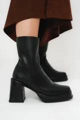 Bota de caña media color negro, de cuero, con horma cuadrada, taco geométrico con textura símil cocodrilo y plataforma.