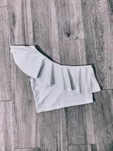 Top corto con un solo hombro y volado grande.