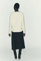 Jersey oversize de punto color crema, con cuello redondo y manga larga. Presenta costuras marcadas en los hombros y los laterales.