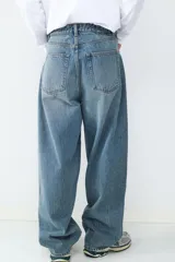 Jean de corte baggy con silueta holgada y relajada, confeccionado en denim de algodón con lavado azul clásico. Presenta diseño de cinco bolsillos, cintura con trabillas y cierre frontal con botón y cremallera.