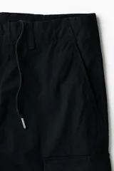 Pantalón cargo negro de sarga de algodón, con bolsillos laterales con solapa en las perneras y corte relajado.