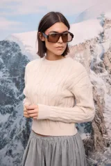 Buzo de punto grueso en color beige, con diseño de trenzas verticales y cuello redondo.