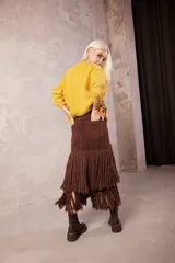 Falda midi de cuero marrón con bolsillos traseros y dos niveles de flecos largos de lana en la parte inferior.