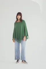 Poncho tejido de punto en color verde, con diseño holgado, cuello redondo y terminación con flecos en el ruedo.