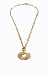 Collar largo de metal dorado con cadena de eslabones medianos y un colgante redondo compuesto por anillos repujados superpuestos con detalle central calado.