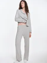 Camisa de pijama de manga larga con cuello solapa y cierre frontal de botones. Presenta un estampado sutil de pequeños corazones sobre una base de color gris melange, con detalles de ribete en contraste en el cuello y la botonera.