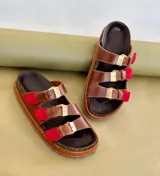 Sandalias de cuero marrón con tres tiras ajustables con hebillas doradas y detalles en rojo.