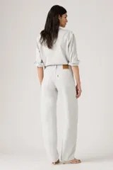 Pantalón de jean estilo baggy con corte barrel, tiro alto y pierna ancha. Presenta un tono gris claro lavado, con costuras reforzadas y diseño de cinco bolsillos.