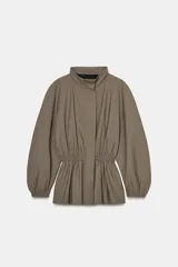 Chaqueta de cuello subido y manga larga con puños elásticos. Presenta un fruncido elástico en la cintura que genera un efecto peplum. Cierre frontal con cremallera oculta por solapa.