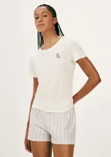 Pijama de algodón compuesto por una remera blanca de manga corta con inscripción frontal y un short a rayas en tonos salmón y beige con cintura elástica.