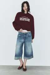 Sudadera de cuello redondo y manga larga, color bordó, con estampado frontal en blanco que dice "Chasing The Sunset's Glow SAN DIEGO 1980 PACIFIC HARBOR".