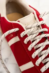 Zapatillas rojas de gamuza con detalles en cuero blanco y suela de goma color caramelo.