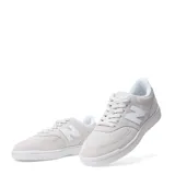 Championes urbanos New Balance modelo 080, color gris claro con detalles en blanco. Presentan una combinación de gamuza y malla en la capellada, con el logo "N" distintivo en los laterales y suela de goma blanca.