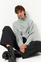 Polera gris de tejido tramado, cuello alto y mangas holgadas.