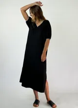 Vestido midi negro con brillo, escote en V con ribete blanco, mangas cortas abullonadas con ribete blanco y aberturas laterales.