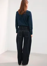 Pantalón de jean de corte recto y tiro medio, en color azul oscuro, con pespuntes en contraste.