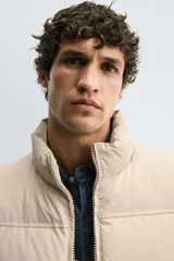 Chaleco acolchado de corte regular, color negro, con cuello alto, cierre frontal con cremallera y bolsillos laterales de vivo.