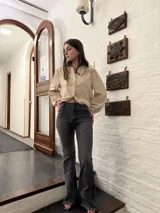 Pantalon de jean gris oscuro con corte recto y botamanga deshilachada. Presenta costuras horizontales decorativas a la altura de los muslos y rodillas, con un diseño de tiro medio.