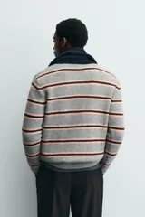 Polo de punto de corte relajado con diseño de rayas horizontales en tonos gris, rosa y marrón. Presenta cuello solapa, cierre frontal con botonadura y mangas largas con puños acanalados.