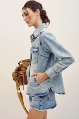 Camisa de denim color celeste con lavado claro, de manga larga, con bolsillos frontales con solapa y cierre de botones metálicos.