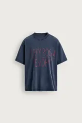 Remera de corte relaxed fit con efecto lavado, cuello redondo y manga corta. Presenta un estampado frontal de texto en tono contrastante.