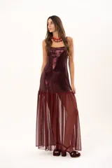 Vestido corto de tirantes finos en color bordó con acabado metalizado brillante. Presenta un corte recto ajustado al cuerpo y un detalle de volado en el ruedo confeccionado en tela traslúcida.