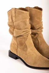 Bota de caña media confeccionada en gamuza color tostado, con diseño arrugado en la caña, punta fina y suela plana con pequeño taco cuadrado.