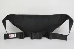 Riñonera negra de nylon con diseño minimalista, cuenta con un parche rojo con el logo de Miami Heat y un tirador de cierre en color naranja. Posee correa regulable y cierre principal.