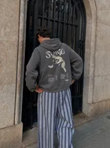 Canguro con capucha gris oscuro, con bolsillo tipo canguro y estampa frontal blanca con texto.